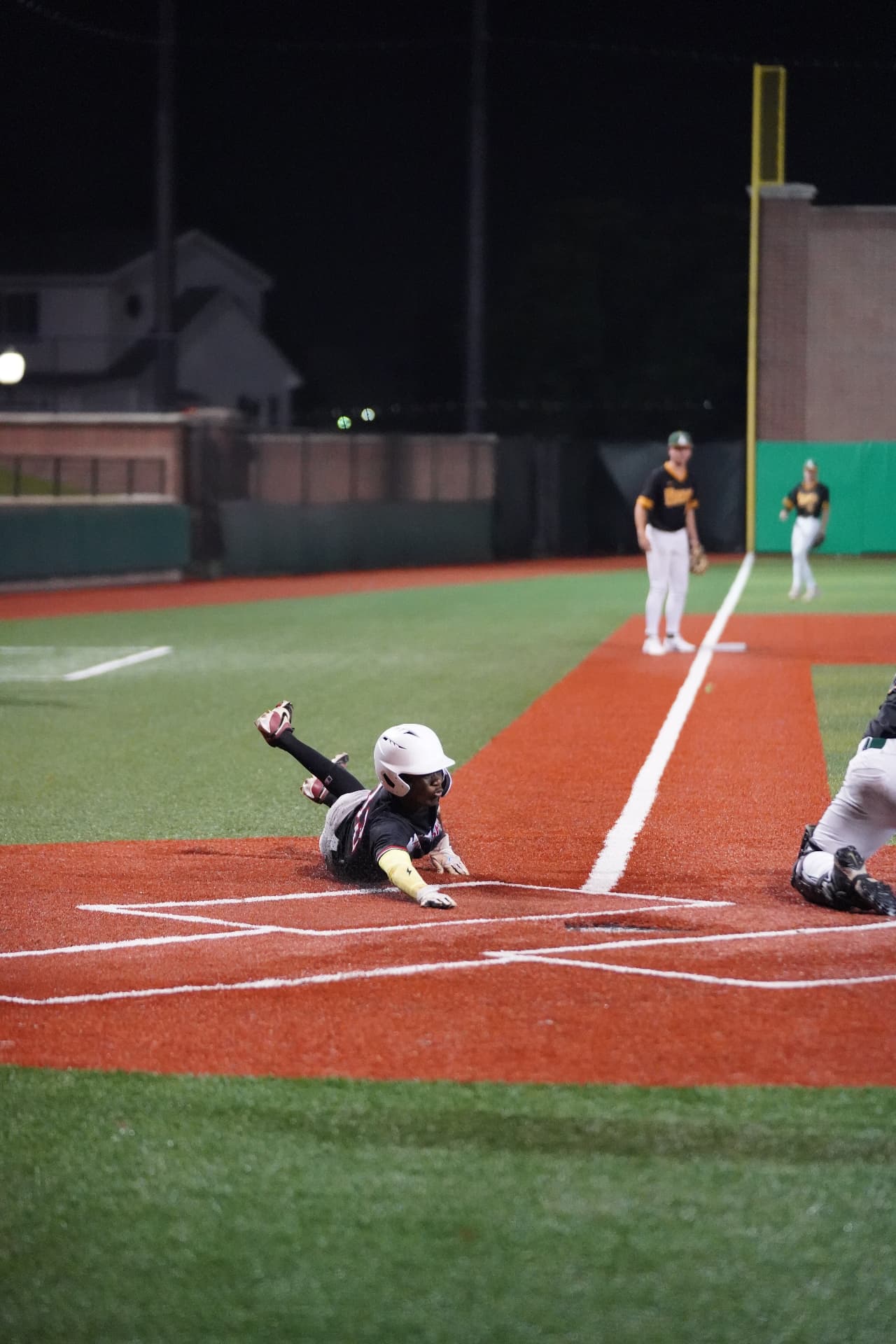 Duane Connolly sliding head-first into home plate under the lights
